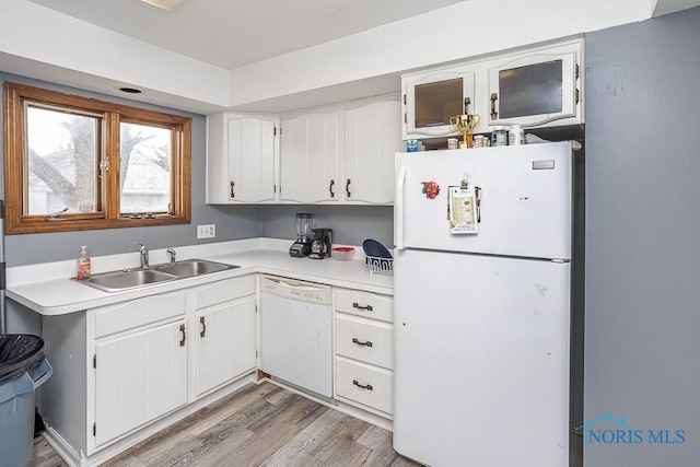 kitchen with white appliances, light countertops, light wood-type flooring, and a sink