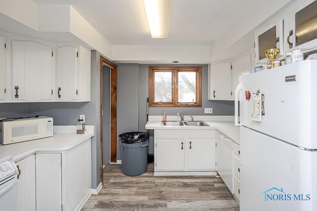 kitchen featuring light wood-style flooring, white appliances, light countertops, and a sink