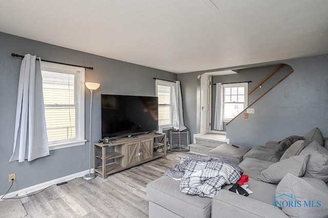 living area featuring baseboards, wood finished floors, and stairs