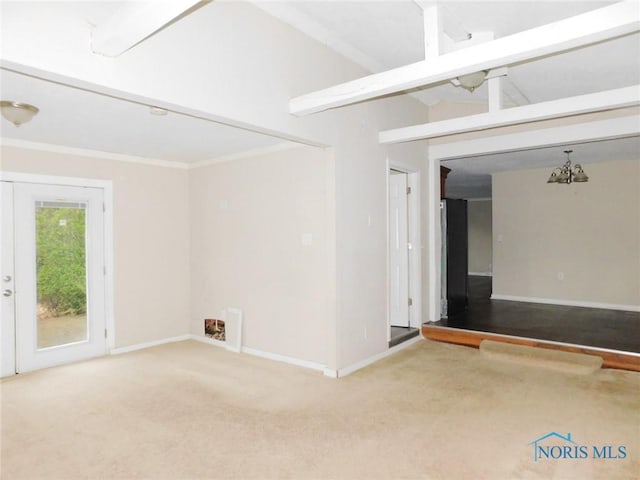 carpeted spare room with baseboards, a chandelier, and crown molding