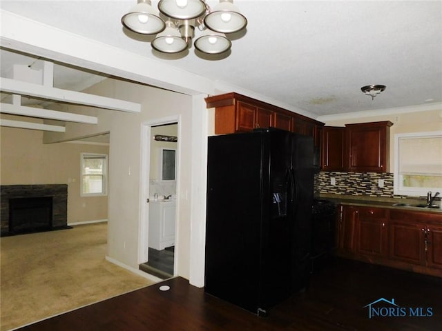 kitchen featuring backsplash, black fridge with ice dispenser, dark brown cabinets, and a fireplace with flush hearth