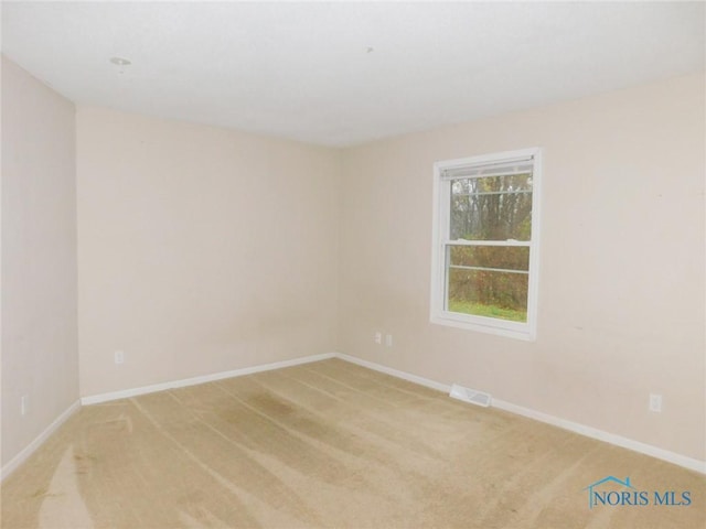 spare room featuring visible vents, baseboards, and light colored carpet