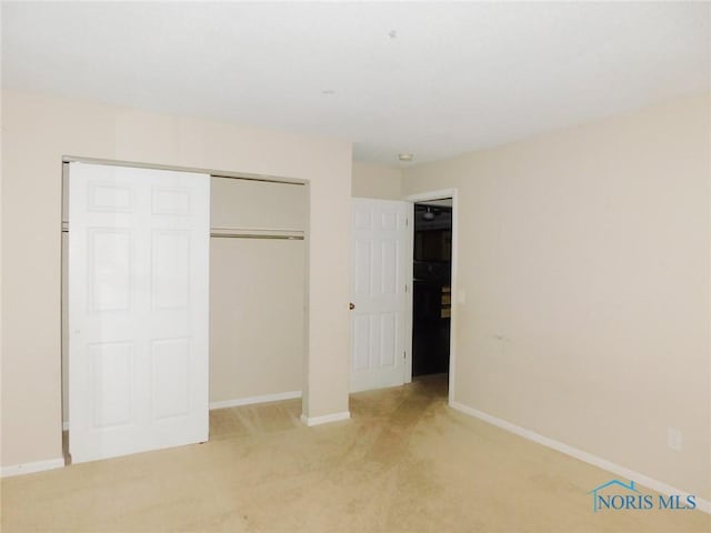 unfurnished bedroom featuring a closet, baseboards, and light colored carpet