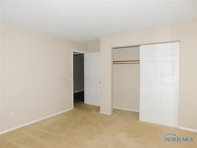 unfurnished bedroom featuring a closet, baseboards, and light carpet