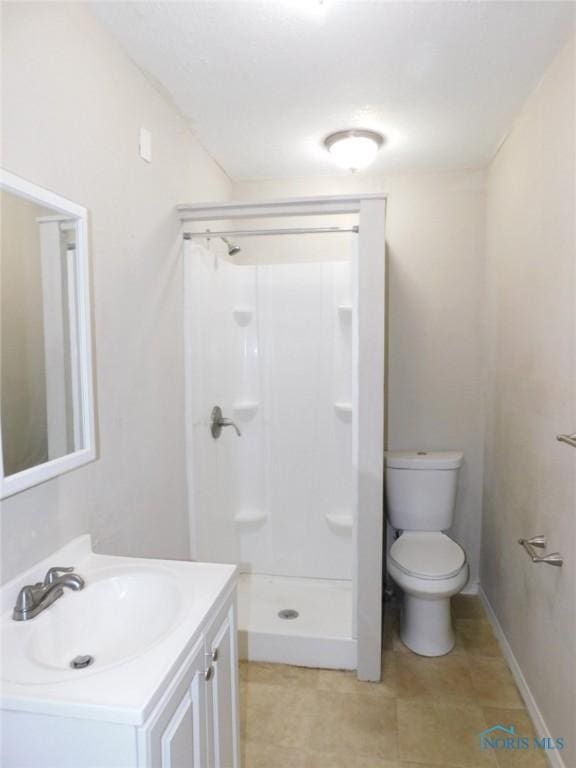 bathroom with toilet, a stall shower, and vanity