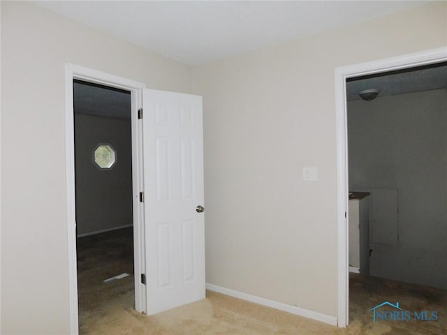 unfurnished bedroom featuring baseboards, a walk in closet, and carpet