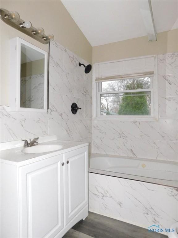 bathroom featuring wood finished floors, tile walls, shower / bath combination, lofted ceiling, and vanity