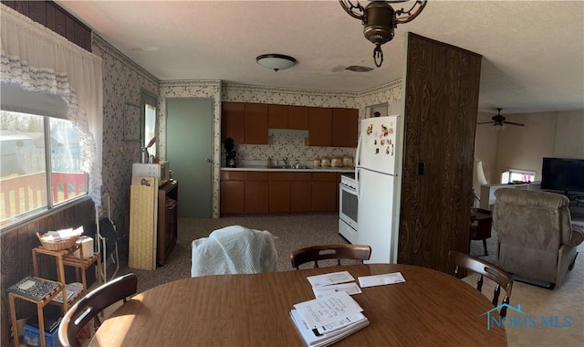 dining room featuring wallpapered walls, light colored carpet, and a ceiling fan