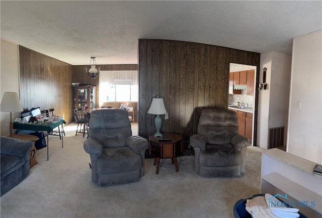 living room with light carpet, visible vents, and wood walls