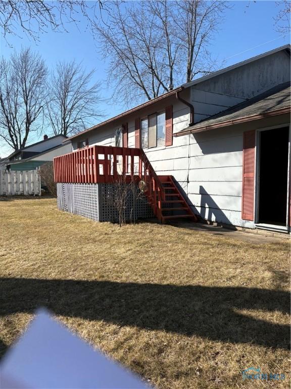 view of home's exterior with a deck, stairway, and a yard