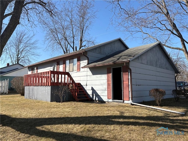 rear view of house featuring a yard, roof with shingles, and stairs