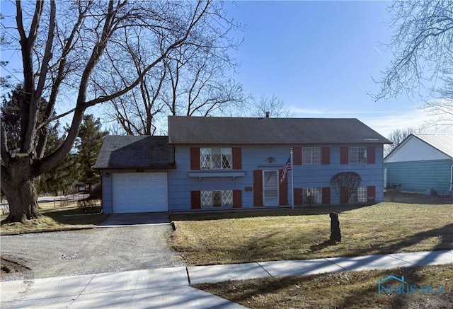 raised ranch featuring a garage, a front yard, and driveway