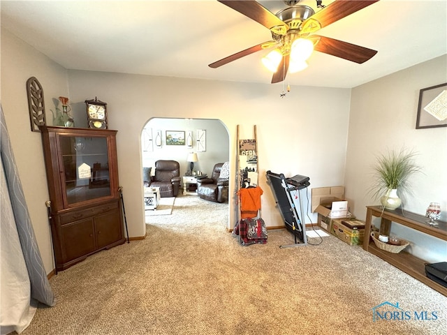 interior space featuring carpet floors, arched walkways, and a ceiling fan