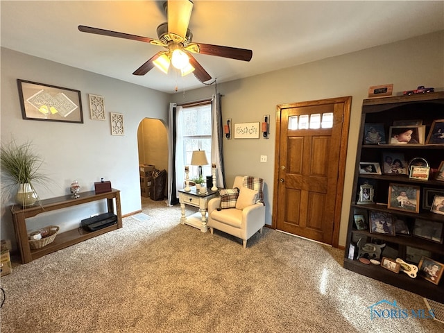 living area featuring baseboards, arched walkways, and a ceiling fan