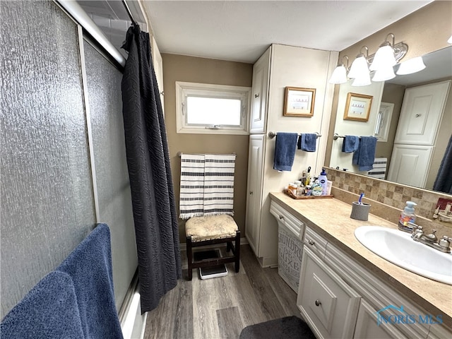 full bathroom with vanity, curtained shower, wood finished floors, and tasteful backsplash