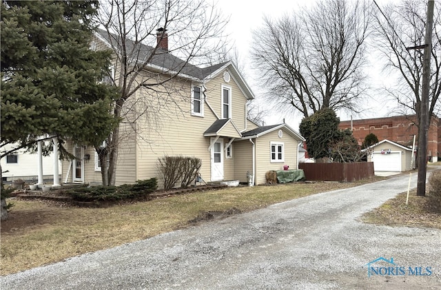 traditional-style house featuring an outdoor structure, a chimney, and fence