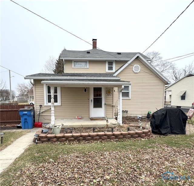 view of front of home featuring a porch, a chimney, and fence