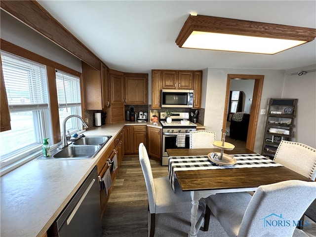 kitchen with dark wood-style floors, a sink, decorative backsplash, light countertops, and stainless steel appliances