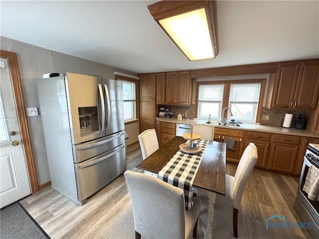 kitchen featuring a sink, stainless steel appliances, backsplash, and light wood finished floors