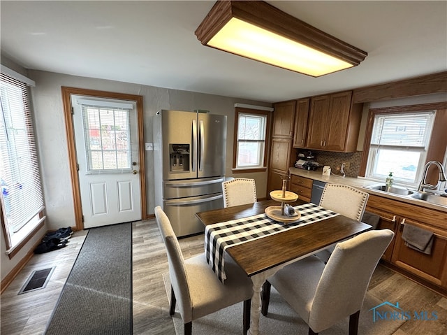 kitchen featuring a wealth of natural light, visible vents, brown cabinets, a sink, and stainless steel appliances