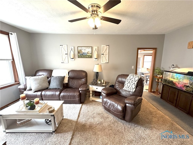 living area featuring carpet floors, a textured ceiling, and a ceiling fan