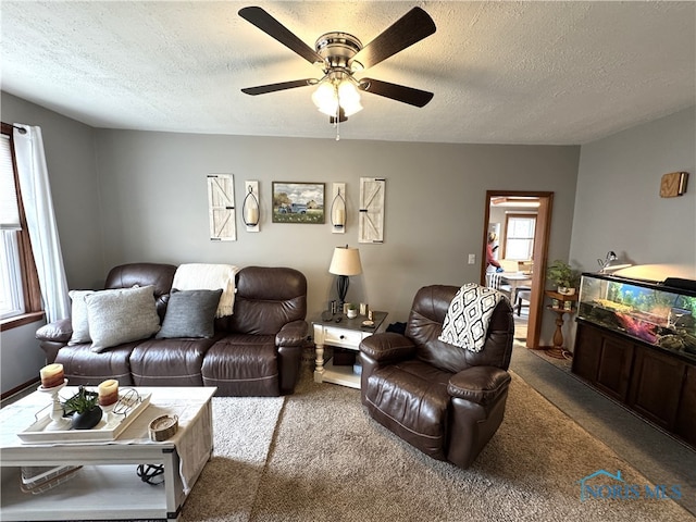 carpeted living area featuring a ceiling fan and a textured ceiling