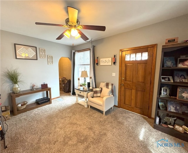 sitting room featuring arched walkways and ceiling fan