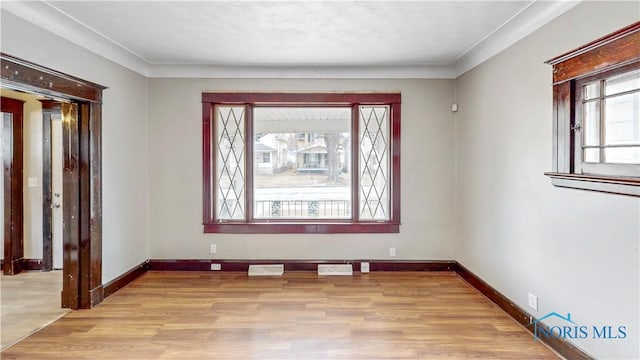 empty room featuring visible vents, baseboards, and wood finished floors