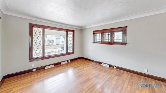 spare room featuring wood finished floors, visible vents, and baseboards