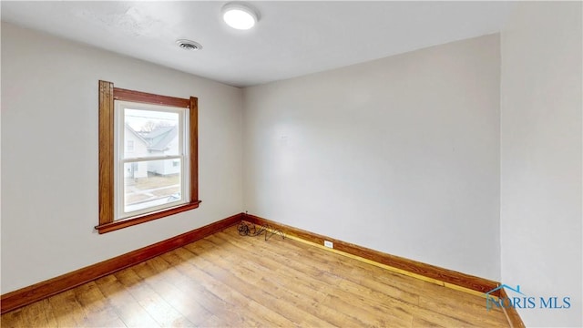 empty room featuring visible vents, baseboards, and wood finished floors