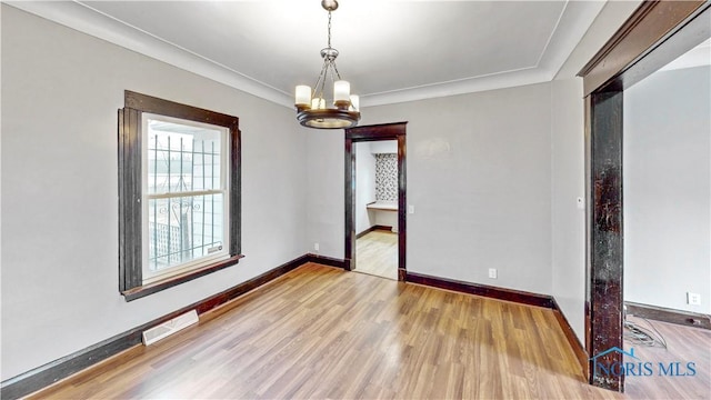 spare room featuring visible vents, baseboards, and wood finished floors