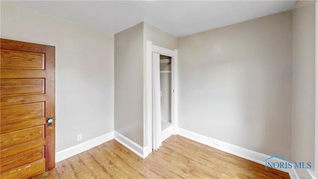 spare room featuring light wood-type flooring and baseboards