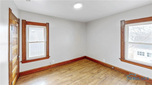 unfurnished room featuring plenty of natural light, light wood-type flooring, and baseboards