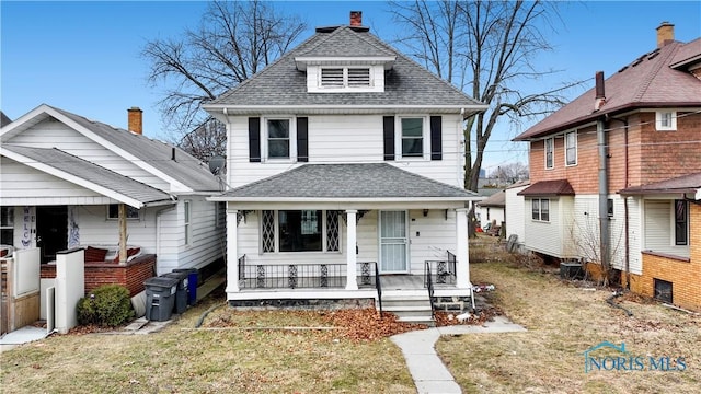 traditional style home featuring covered porch, a front lawn, and a shingled roof