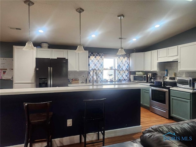 kitchen with visible vents, a breakfast bar, under cabinet range hood, stainless steel appliances, and light countertops