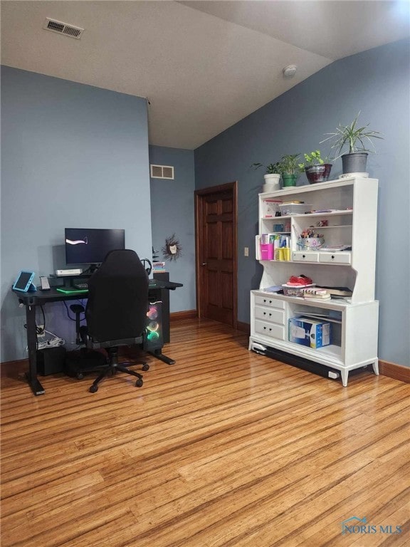 office space featuring visible vents, baseboards, wood finished floors, and vaulted ceiling