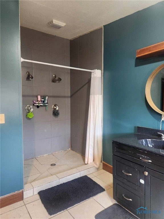 bathroom with vanity, tile patterned floors, baseboards, and a stall shower