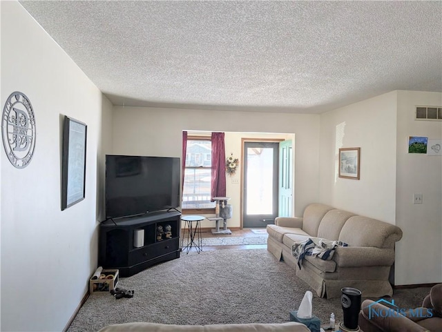 carpeted living room featuring visible vents and a textured ceiling