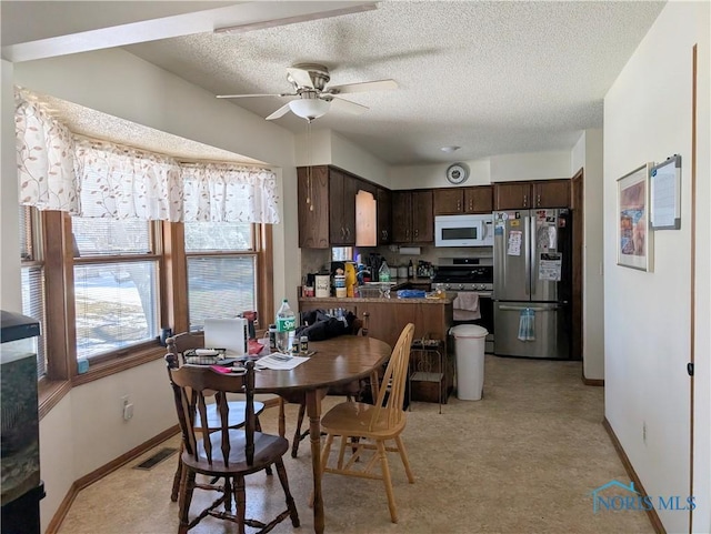 dining room featuring a ceiling fan, a healthy amount of sunlight, visible vents, and a textured ceiling