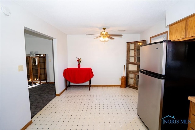 kitchen with brown cabinets, a ceiling fan, freestanding refrigerator, and baseboards