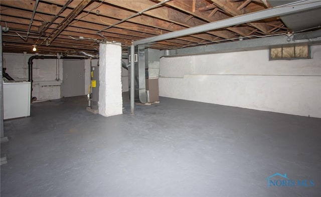 unfinished below grade area featuring heating unit, washer / dryer, and water heater