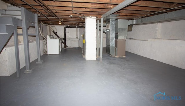 unfinished basement featuring washer / dryer and heating unit