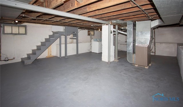 unfinished basement featuring stairway, heating unit, and washer / dryer