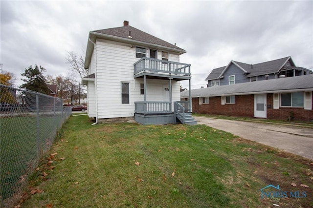 exterior space featuring a lawn, a chimney, a balcony, and fence