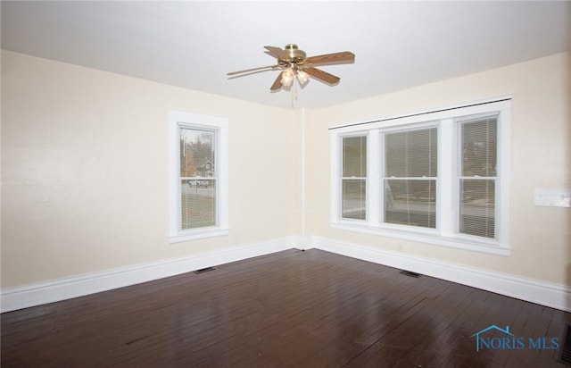 unfurnished room featuring dark wood finished floors, visible vents, baseboards, and ceiling fan