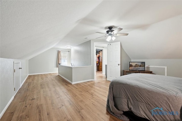 bedroom with a ceiling fan, lofted ceiling, wood finished floors, and baseboards