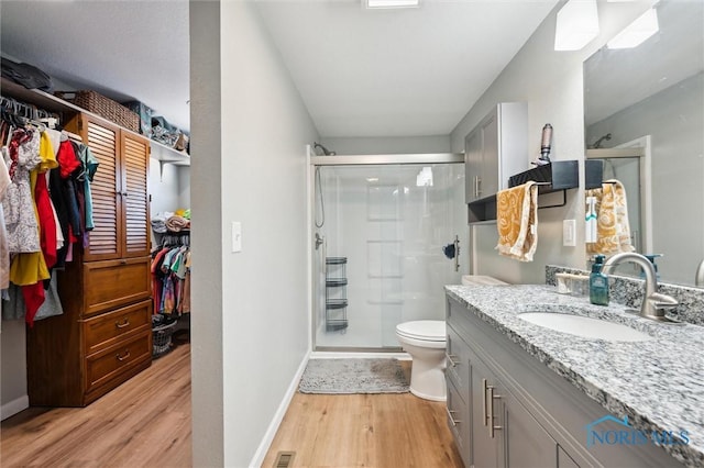 full bathroom with a shower stall, baseboards, toilet, wood finished floors, and vanity