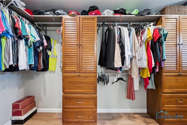 walk in closet with wood finished floors