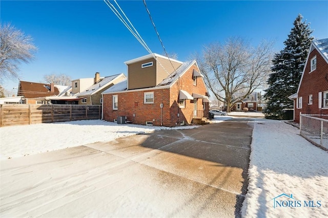 exterior space with brick siding, central AC, and fence