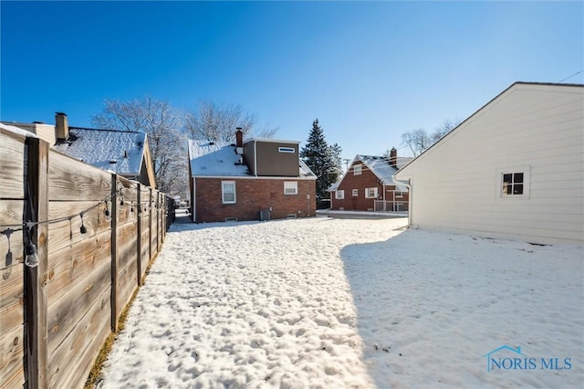 snowy yard featuring fence